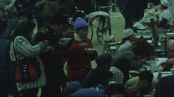 Movie still from “The Story of Qiu Ju” (1992), directed by Yimou Zhang – A group of people sitting around eating food; Medium shot, High angle