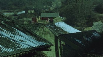 Movie still from “The Story of Qiu Ju” (1992), directed by Yimou Zhang – A view of some buildings and a person standing on the roof; Extreme Wide shot, High angle