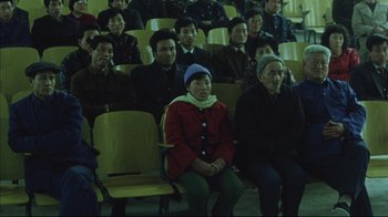 Movie still from “The Story of Qiu Ju” (1992), directed by Yimou Zhang – A group of people sitting in rows in a room; Wide shot, High angle