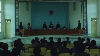 Movie still from “The Story of Qiu Ju” (1992), directed by Yimou Zhang – A group of people sitting in front of an audience; Extreme Wide shot, High angle