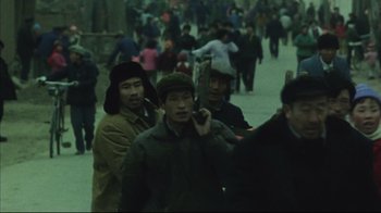 Movie still from “The Story of Qiu Ju” (1992), directed by Yimou Zhang – A group of people walking down a street; Medium shot, High angle