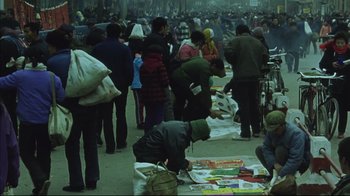 Movie still from “The Story of Qiu Ju” (1992), directed by Yimou Zhang – A group of people standing around in a market area; Wide shot, High angle