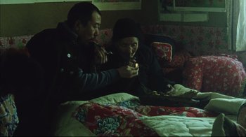 Movie still from “The Story of Qiu Ju” (1992), directed by Yimou Zhang – Two people sitting on a couch in a room; Medium shot, High angle