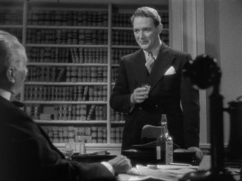 Movie still from “The Story of Temple Drake” (1933), directed by Stephen Roberts – A man in a suit and tie holding a drink; Medium shot, Over the shoulder angle