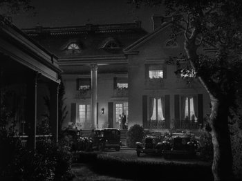 Movie still from “The Story of Temple Drake” (1933), directed by Stephen Roberts – A black - and - white photo of a house at night; Extreme Wide shot, Low angle
