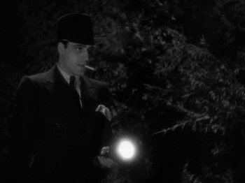 Movie still from “The Story of Temple Drake” (1933), directed by Stephen Roberts – A black and white photo of a man holding a flashlight; Medium shot, Low angle