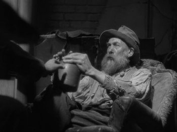 Movie still from “The Story of Temple Drake” (1933), directed by Stephen Roberts – An old man sitting on a chair holding a bottle; Medium shot, Low angle