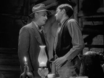 Movie still from “The Story of Temple Drake” (1933), directed by Stephen Roberts – Two men standing next to each other in front of an oil lamp; Medium shot, Low angle
