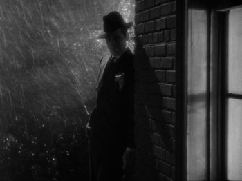 Movie still from “The Story of Temple Drake” (1933), directed by Stephen Roberts – A black and white photo of a man in a suit and hat; Medium shot, Over the shoulder angle