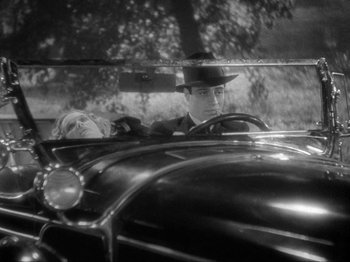 Movie still from “The Story of Temple Drake” (1933), directed by Stephen Roberts – A man and a woman sitting in the driver's seat of an antique car; Medium shot, High angle