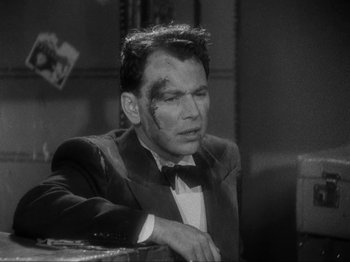 Movie still from “The Story of Temple Drake” (1933), directed by Stephen Roberts – A black and white photo of a man in a suit and bow tie; Close Up shot, High angle