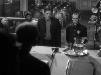 Movie still from “The Story of Temple Drake” (1933), directed by Stephen Roberts – A man and a woman standing in front of an audience; Medium shot, Over the shoulder angle