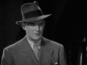Movie still from “The Story of Temple Drake” (1933), directed by Stephen Roberts – A black and white photo of a man in a suit and a hat; Close Up shot, High angle