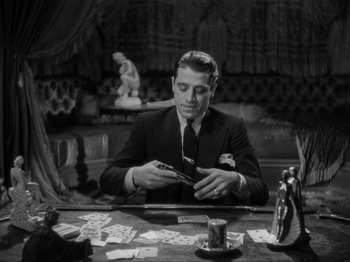 Movie still from “The Story of Temple Drake” (1933), directed by Stephen Roberts – A black and white photo of a man at a table with cards; Medium shot, High angle