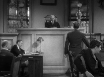 Movie still from “The Story of Temple Drake” (1933), directed by Stephen Roberts – Two men are sitting in a court room in front of a judge; Wide shot, Over the shoulder angle
