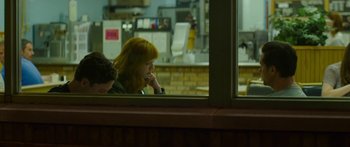 Movie still from “The Strangers: Prey at Night” (2018), directed by Johannes Roberts – A woman sitting in front of a store window; Medium shot, Over the shoulder angle