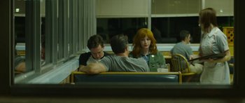 Movie still from “The Strangers: Prey at Night” (2018), directed by Johannes Roberts – A group of people sitting at a table in front of a window; Medium shot, Over the shoulder angle