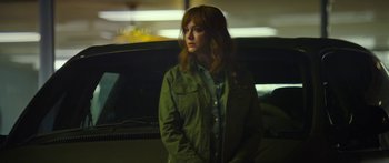 Movie still from “The Strangers: Prey at Night” (2018), directed by Johannes Roberts – A woman in a green jacket standing next to a car; Medium shot, Low angle