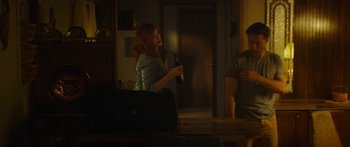 Movie still from “The Strangers: Prey at Night” (2018), directed by Johannes Roberts – A woman is holding a beer in her hand while standing next to a man; Medium shot, Over the shoulder angle