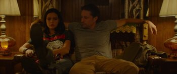 Movie still from “The Strangers: Prey at Night” (2018), directed by Johannes Roberts – A man and a woman sitting on a couch together; Medium shot, Over the shoulder angle
