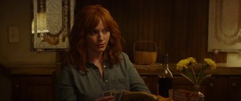 Movie still from “The Strangers: Prey at Night” (2018), directed by Johannes Roberts – A woman sitting in front of a bottle of wine; Medium shot, Over the shoulder angle