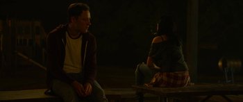 Movie still from “The Strangers: Prey at Night” (2018), directed by Johannes Roberts – A man and a woman sitting on a wooden bench; Medium shot, Over the shoulder angle