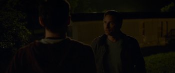 Movie still from “The Strangers: Prey at Night” (2018), directed by Johannes Roberts – A man standing next to another man in a dark room; Medium shot, Over the shoulder angle