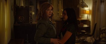Movie still from “The Strangers: Prey at Night” (2018), directed by Johannes Roberts – Two women standing next to each other in a dark room; Medium shot, Over the shoulder angle