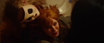 A woman with red hair is laying in a bathroom