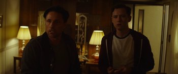 Movie still from “The Strangers: Prey at Night” (2018), directed by Johannes Roberts – Two men standing next to each other in front of a lamp; Medium shot, Over the shoulder angle