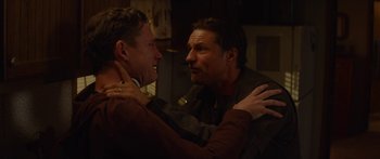 Movie still from “The Strangers: Prey at Night” (2018), directed by Johannes Roberts – Two men are hugging in a dark room; Close Up shot, Over the shoulder angle