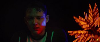 Movie still from “The Strangers: Prey at Night” (2018), directed by Johannes Roberts – A young man in a dark room with neon lights on the background; Close Up shot, Low angle