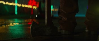 Movie still from “The Strangers: Prey at Night” (2018), directed by Johannes Roberts – An axe sitting on top of the ground in front of lights; Extreme Close Up shot, Low angle