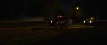 Movie still from “The Strangers: Prey at Night” (2018), directed by Johannes Roberts – A police car parked on the side of the road at night; Extreme Wide shot, Low angle