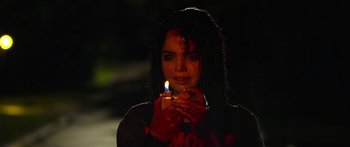 Movie still from “The Strangers: Prey at Night” (2018), directed by Johannes Roberts – A woman holding a lit candle with blood on her face; Medium shot, High angle