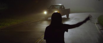 Movie still from “The Strangers: Prey at Night” (2018), directed by Johannes Roberts – A person standing in the middle of the road at night; Medium shot, Low angle
