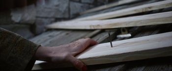 Movie still from “The Stylist” (2020), directed by Jill Gevargizian – A hand holding a nail on top of a wooden board; Extreme Close Up shot, High angle