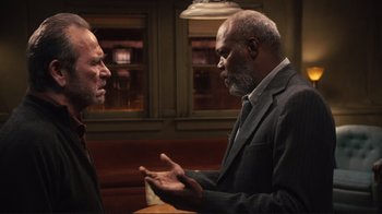 Movie still from “The Sunset Limited” (2011), directed by Tommy Lee Jones – Two men in business suits talking to each other; Medium shot, Over the shoulder angle