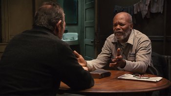 Movie still from “The Sunset Limited” (2011), directed by Tommy Lee Jones – Two men sitting at a table talking to each other; Medium shot, Over the shoulder angle