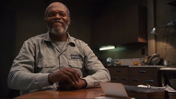 Movie still from “The Sunset Limited” (2011), directed by Tommy Lee Jones – An older man sitting at a table in front of a laptop computer; Medium shot, Low angle