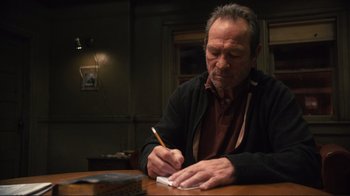Movie still from “The Sunset Limited” (2011), directed by Tommy Lee Jones – An older man writing on a piece of paper; Medium shot, High angle