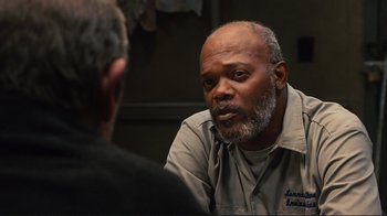 Movie still from “The Sunset Limited” (2011), directed by Tommy Lee Jones – A man sitting in front of another man in front of a wall; Close Up shot, Over the shoulder angle