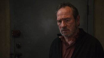 Movie still from “The Sunset Limited” (2011), directed by Tommy Lee Jones – An older man is smoking a pipe in a dark room; Close Up shot, Low angle