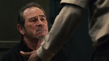 Movie still from “The Sunset Limited” (2011), directed by Tommy Lee Jones – An older man is looking at the arm of a younger man; Close Up shot, Over the shoulder angle