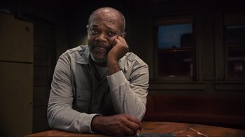 Movie still from “The Sunset Limited” (2011), directed by Tommy Lee Jones – An older man sitting at a table with a cell phone; Close Up shot, Low angle