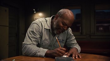 Movie still from “The Sunset Limited” (2011), directed by Tommy Lee Jones – An older man writing on a piece of paper; Medium shot, High angle