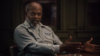 Movie still from “The Sunset Limited” (2011), directed by Tommy Lee Jones – An older man sitting at a table with his hands outstreched; Close Up shot, Over the shoulder angle