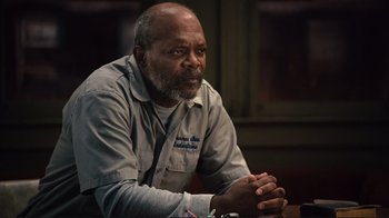 Movie still from “The Sunset Limited” (2011), directed by Tommy Lee Jones – An older man sitting at a table with his hands clasped together; Close Up shot, Low angle