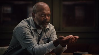 Movie still from “The Sunset Limited” (2011), directed by Tommy Lee Jones – An older man sitting at a table with his hands raised; Close Up shot, High angle