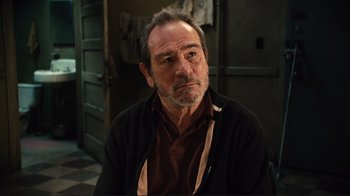 Movie still from “The Sunset Limited” (2011), directed by Tommy Lee Jones – An older man sitting in front of an open door; Close Up shot, Over the shoulder angle